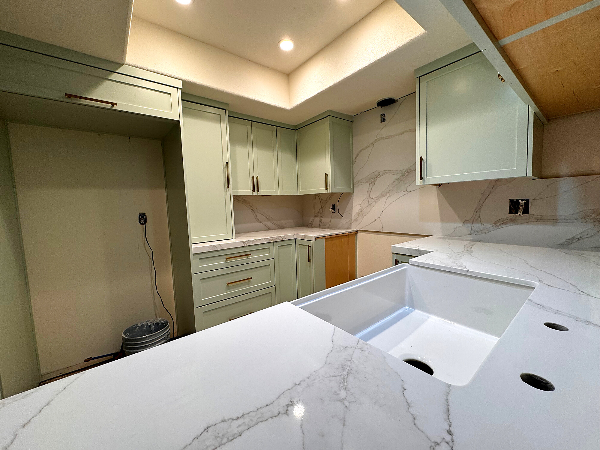 Sage green cabinetry with calacatta marble countertops and brass hardware