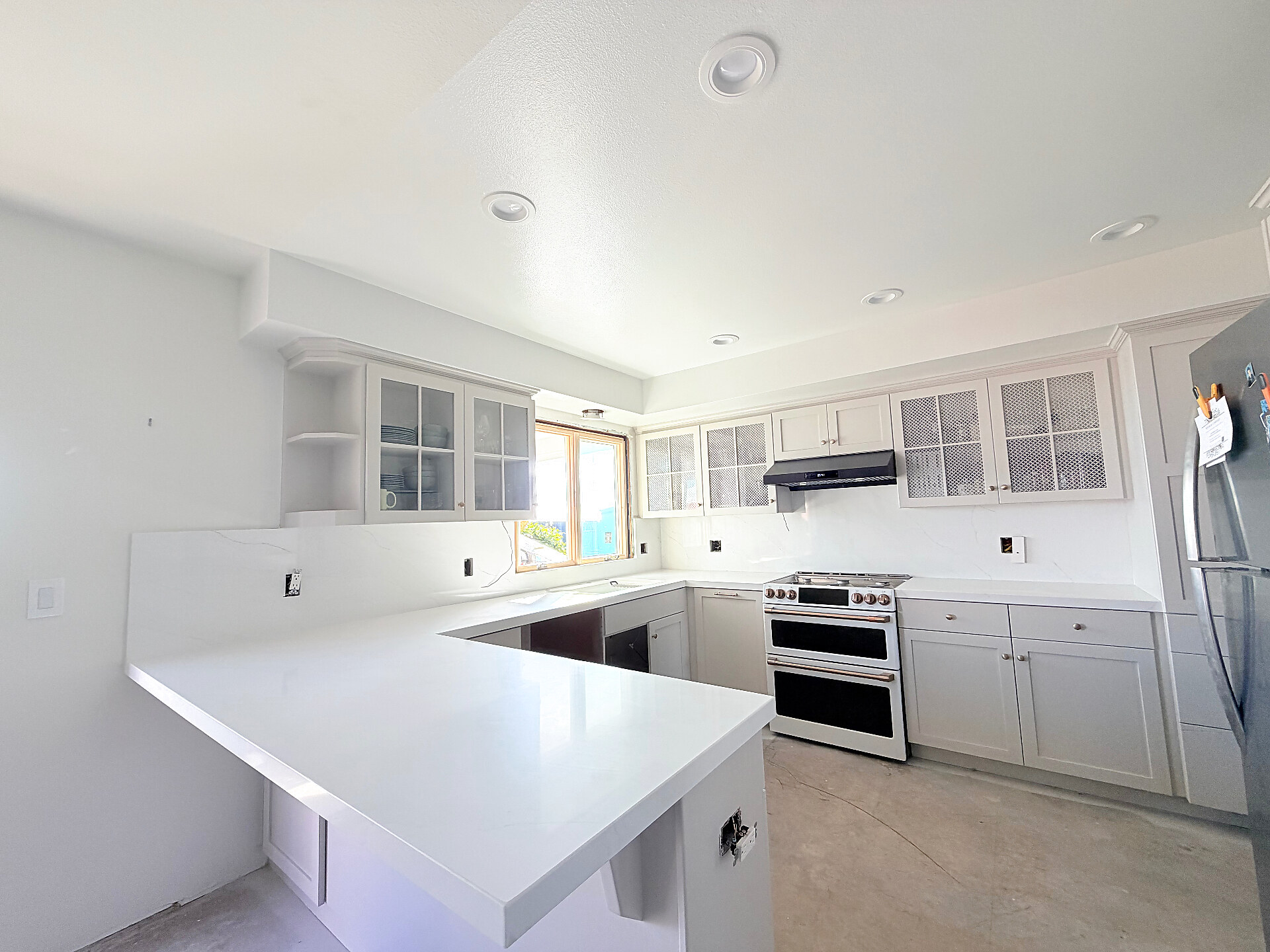 Bright white quartz U-shaped kitchen with double oven — Ventura County remodel