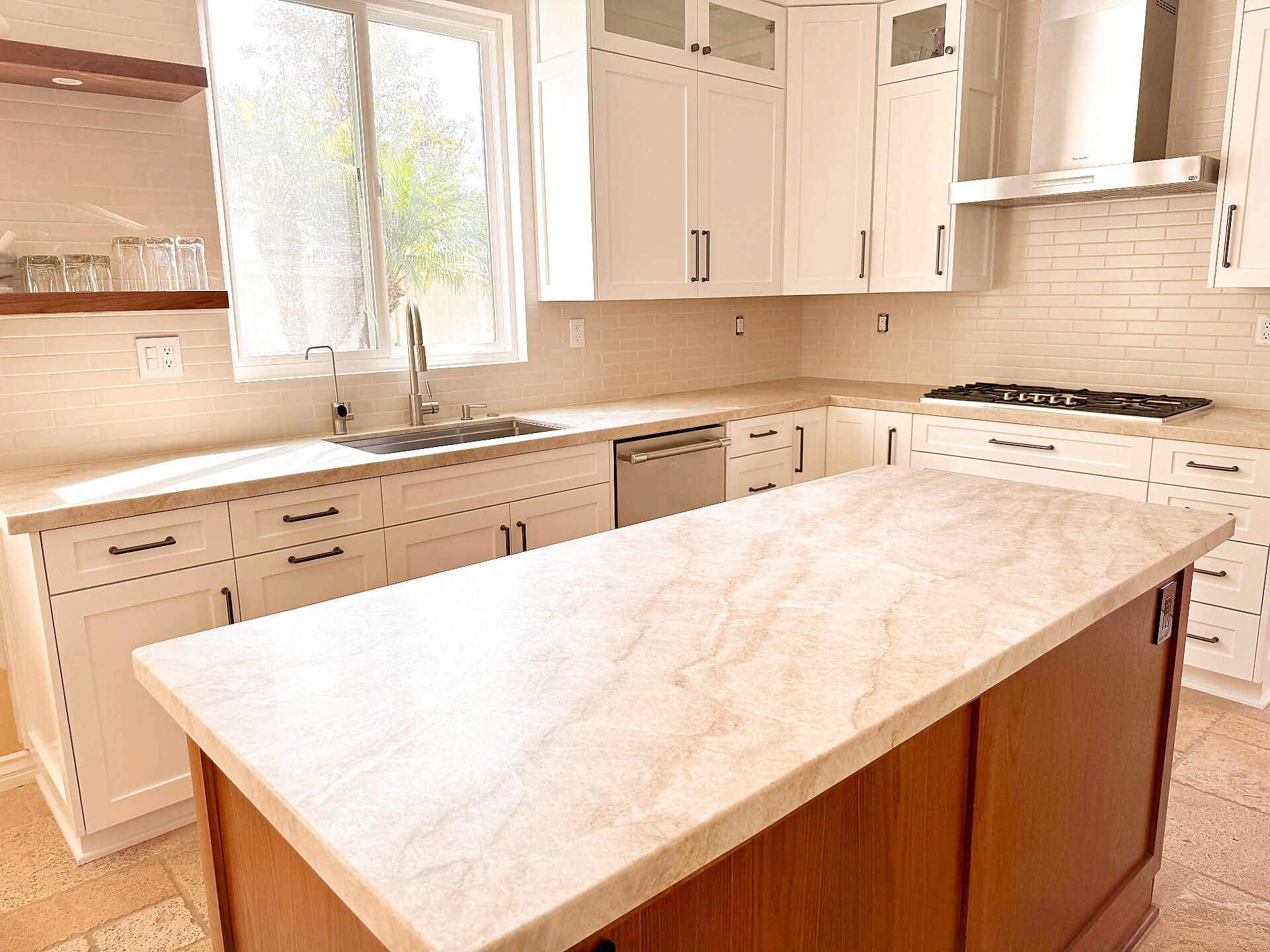 Taj Mahal quartzite island with white shaker cabinets and subway backsplash